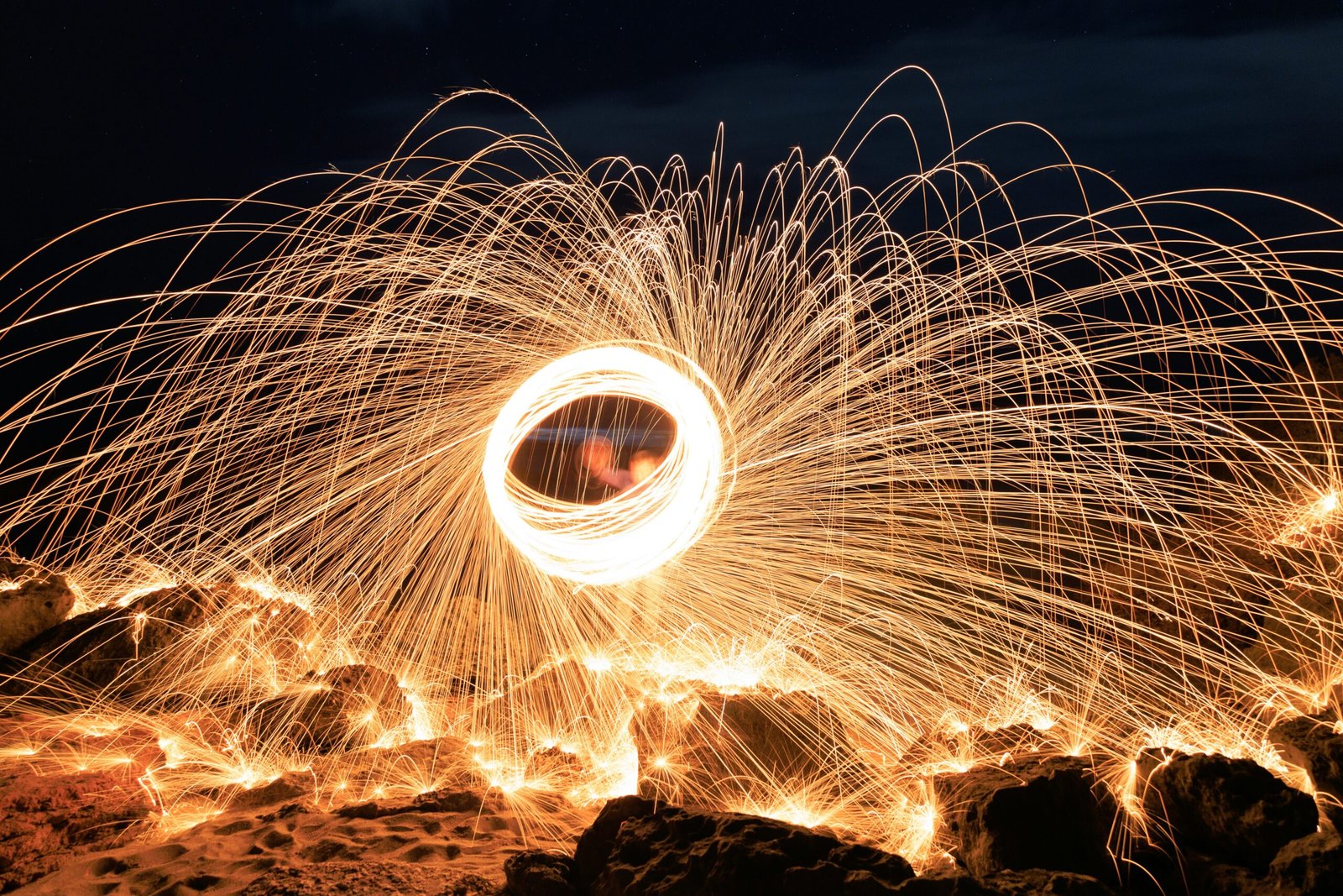 a firework spinning in the air over rocks