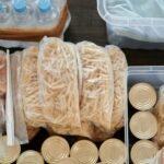 Aerial shot of pantry essentials including pasta, canned food, and bread packaged in plastic bags.