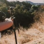 A person aiming a bow in a scenic, sunny outdoor setting, perfect for adventure themes.