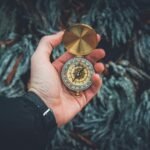 A close-up shot of a hand holding a vintage compass against a natural background.